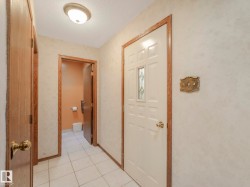 Entryway featuring a paneled door with decorative glass inserts, white ceramic tile flooring, and wood-finish trim - 