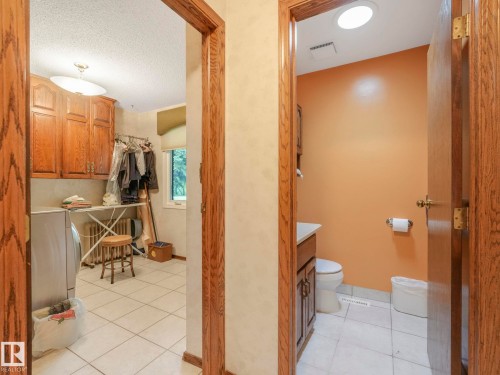 Dedicated utility room with wood-finish cabinetry, tile flooring, and a window for natural light - 11921 231 Street, Edmonton, AB 