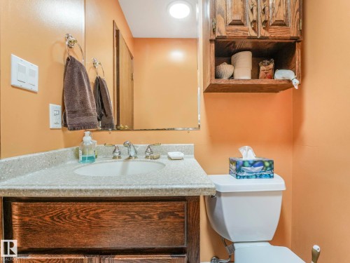 Bathroom vanity featuring a light-toned speckled countertop, an undermount sink, and a dark wood-finish cabinet - 11921 231 Street, Edmonton, AB 