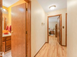 Hallway with wood-finish flooring, two panel doors, and neutral wall paint - 