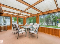 Sunroom featuring wood paneling, extensive window walls, translucent ceiling panels, and neutral carpeting - 