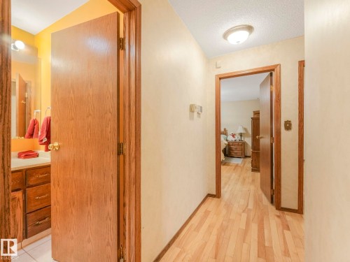 Hallway with wood-finish flooring, two panel doors, and neutral wall paint - 11921 231 Street, Edmonton, AB 