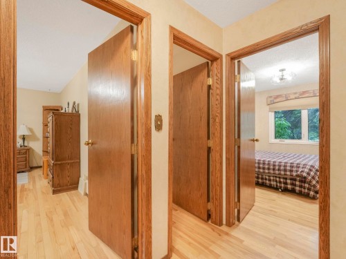 Hardwood flooring extends throughout this interior hallway, featuring solid wood doors with brass hardware, and a neutral wall color - 11921 231 Street, Edmonton, AB 