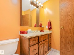 Bathroom featuring a vanity with wood-finish cabinetry, a light-colored countertop with an integrated sink, and a rectangular mirror - 