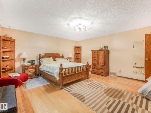 Spacious room featuring light wood-finish flooring, neutral wall tones, and a ceiling-mounted light fixture - 11921 231 Street, Edmonton, AB 