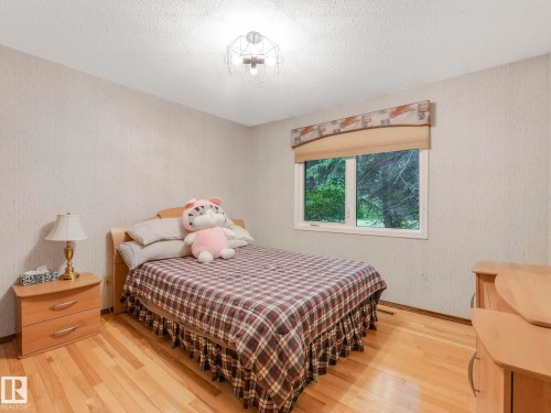 Hardwood-finish flooring enhancing a neutral-toned room with a large window and a ceiling-mounted light fixture - 11921 231 Street, Edmonton, AB 