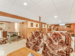 Finished lower level featuring a drop ceiling with recessed lighting, wood-paneled walls, and plush carpeting - 