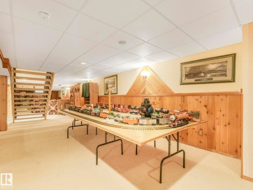 Expansive room featuring light-toned carpeting and wood paneling along the lower walls - 11921 231 Street, Edmonton, AB 