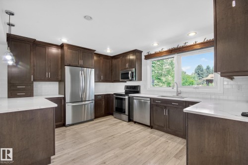 Kitchen featuring dark wood cabinetry, light countertops, subway tile backsplash, and light wood-finish flooring - 3 Galaxy Way, Sherwood Park, AB 