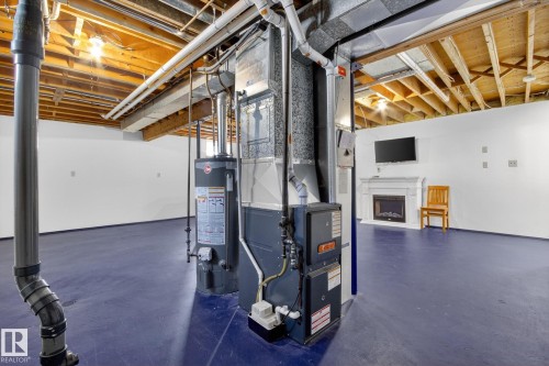 Expansive finished lower level featuring a fireplace with a white mantel, exposed wood joists, and a painted concrete floor - 3 Galaxy Way, Sherwood Park, AB 