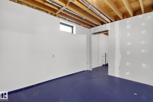 Unfinished lower level with exposed ceiling joists and framing, a high-set window, and a durable blue floor - 3 Galaxy Way, Sherwood Park, AB 