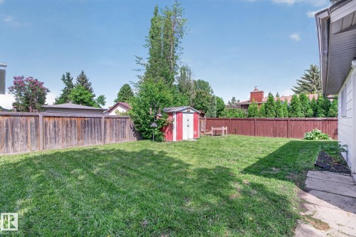 Expansive backyard featuring a lush lawn, a red and white storage shed, and durable wood fencing - 3 Galaxy Way, Sherwood Park, AB 