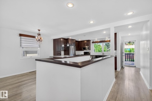 Open-concept kitchen and dining area featuring recessed lighting, dark wood-finish cabinetry, stainless steel appliances, and wood-finish flooring - 3 Galaxy Way, Sherwood Park, AB 