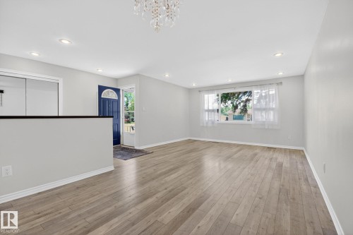 Spacious open-concept room featuring wood-finish flooring, recessed lighting, and a crystal chandelier - 3 Galaxy Way, Sherwood Park, AB 