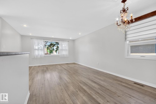 Spacious room featuring wood-finish flooring, recessed lighting, and a crystal chandelier - 3 Galaxy Way, Sherwood Park, AB 