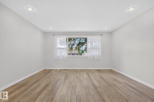 Spacious interior featuring wood-finish flooring, recessed lighting, and a large window - 3 Galaxy Way, Sherwood Park, AB 