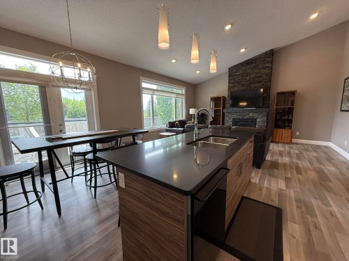 Open-concept living area featuring a kitchen island with dual sinks and a dark countertop - 2 104 Allard Link, Edmonton, AB 