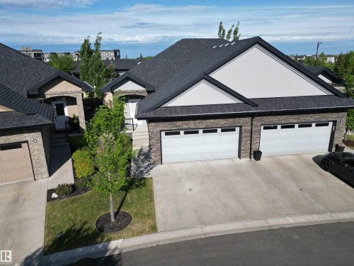 Stone facade residence featuring a double-car garage and a paved driveway - 2 104 Allard Link, Edmonton, AB 