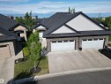 Stone facade residence featuring a double-car garage and a paved driveway - 2 104 Allard Link, Edmonton, AB 