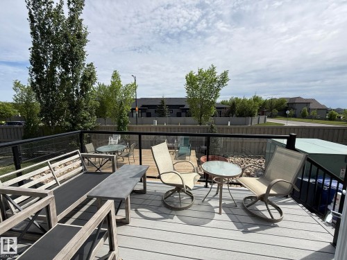 Spacious outdoor deck featuring gray composite decking and a black metal railing with glass panels - 2 104 Allard Link, Edmonton, AB 