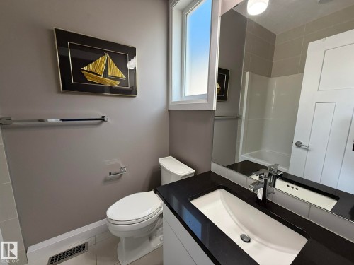 Full bathroom featuring a single window, a toilet, and a vanity with a dark countertop and an undermount sink - 2 104 Allard Link, Edmonton, AB 