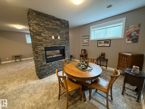 Stone-clad fireplace feature wall with an integrated electric fireplace - 2 104 Allard Link, Edmonton, AB 