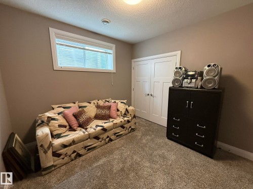Carpeted room featuring a window with blinds, neutral wall paint, and a white paneled door - 2 104 Allard Link, Edmonton, AB 