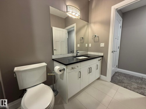 Basement Full 3pc Bathroom with a white vanity & GRANITE Countertop, integrated sink, and contemporary light fixture - 2 104 Allard Link, Edmonton, AB 