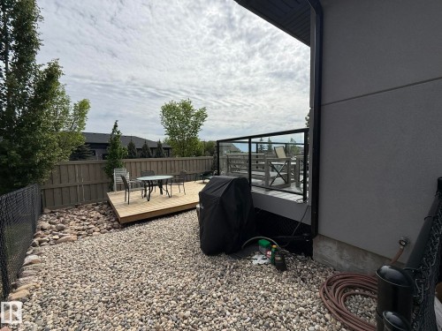 Outdoor space featuring a multi-level composite deck with glass panel railings, a fenced perimeter, and gravel landscaping - 2 104 Allard Link, Edmonton, AB 