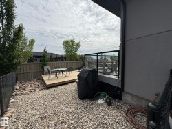 Outdoor space featuring a multi-level composite deck with glass panel railings, a fenced perimeter, and gravel landscaping - 