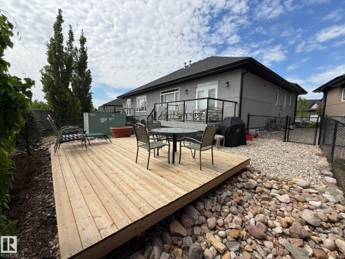 Spacious backyard featuring a large wood deck, gravel landscaping, and a chain-link fence - 2 104 Allard Link, Edmonton, AB 