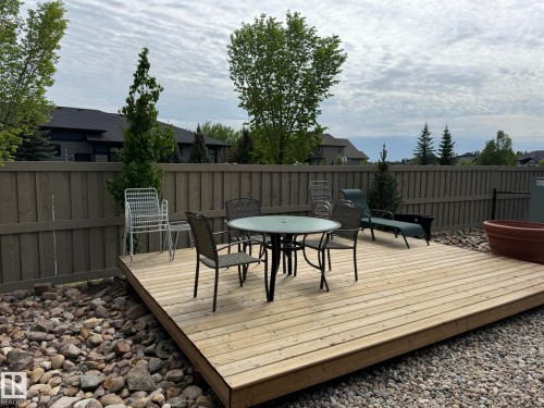 Spacious outdoor deck surrounded by natural stone landscaping and a wooden privacy fence - 2 104 Allard Link, Edmonton, AB 
