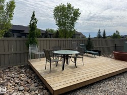 Spacious outdoor deck surrounded by natural stone landscaping and a wooden privacy fence - 