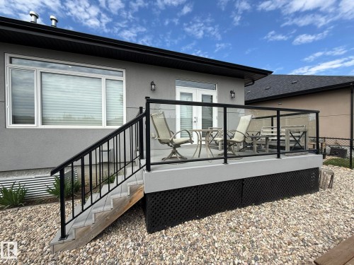 Rear exterior deck featuring glass railings and black metal balusters - 2 104 Allard Link, Edmonton, AB 