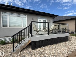 Rear exterior deck featuring glass railings and black metal balusters - 