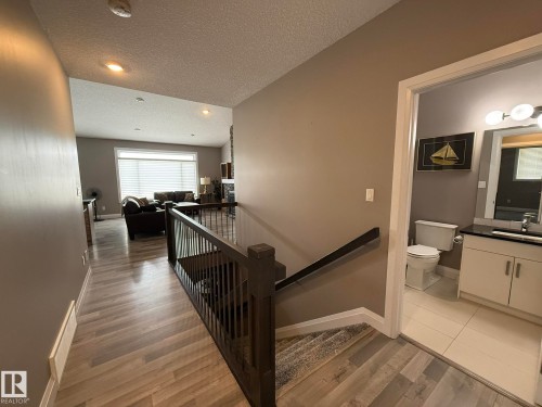 Open-concept living space featuring wood-finish flooring, recessed lighting, and a large window with horizontal blinds - 2 104 Allard Link, Edmonton, AB 