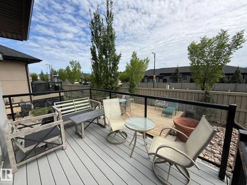 Multi-level deck featuring composite and wood-finish decking, black aluminum railings with glass panels, and a landscaped rock bed - 2 104 Allard Link, Edmonton, AB 