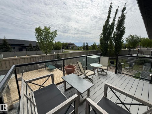 Spacious elevated deck featuring composite decking, glass railing, and a lower wood deck - 2 104 Allard Link, Edmonton, AB 