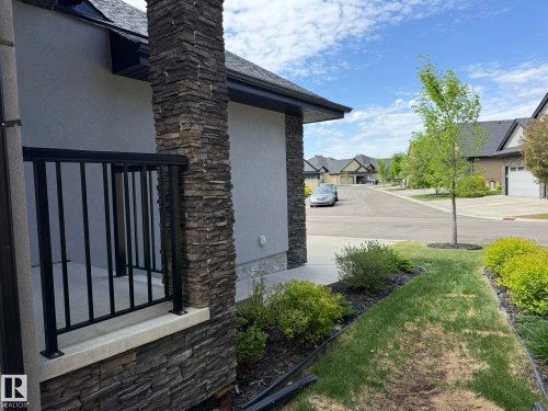 Exterior featuring a decorative stacked stone pillar, stucco siding, and dark gutters - 2 104 Allard Link, Edmonton, AB 