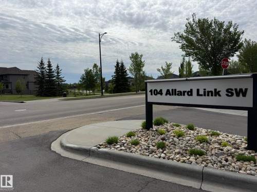 Street signage for 104 Allard Link SW featuring a landscaped base with river rock and low-lying shrubs - 2 104 Allard Link, Edmonton, AB 