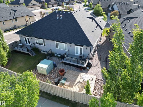 Rear exterior featuring two levels of outdoor living space, including a wooden deck and a ground-level patio with gravel landscaping - 2 104 Allard Link, Edmonton, AB 