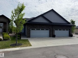 Contemporary exterior featuring dark stacked stone accents, a dark asphalt shingle roof, and a light gray gable - 