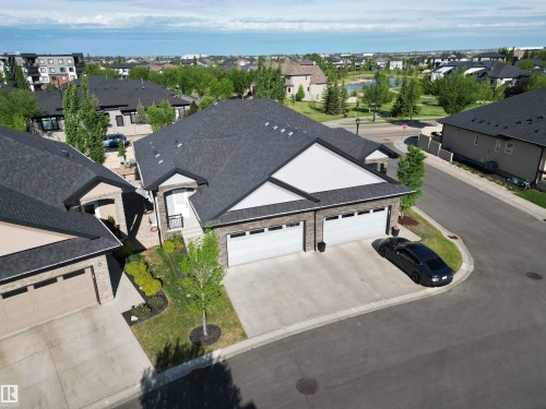 Modern residential property featuring a dark shingle roof, light brick facade with white siding accents, and an attached two-car garage - 2 104 Allard Link, Edmonton, AB 