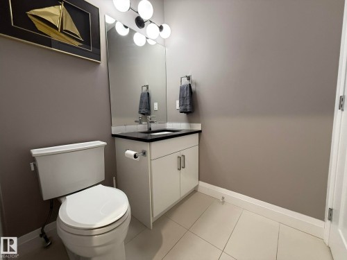 Modern powder room featuring a white vanity with black countertop, under-mount sink, and chrome faucet - 2 104 Allard Link, Edmonton, AB 