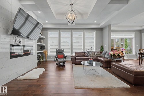 Spacious living area featuring rich wood-finish flooring and a tray ceiling with recessed lighting - 3036 59 Avenue, Rural Leduc County, AB 