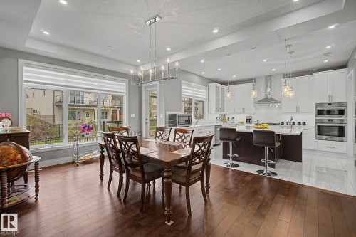 Open-concept kitchen and dining area with hardwood-finish flooring, recessed lighting, and a tray ceiling - 3036 59 Avenue, Rural Leduc County, AB 