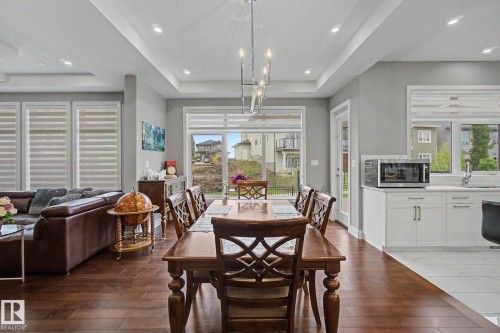 Expansive dining area featuring wood-finish flooring and a contemporary chandelier - 3036 59 Avenue, Rural Leduc County, AB 