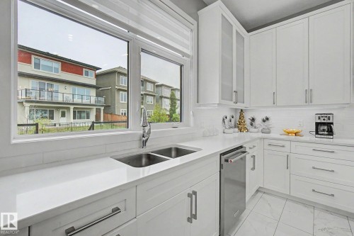 Modern kitchen featuring white cabinetry, a double basin stainless steel sink, and light-toned countertops - 3036 59 Avenue, Rural Leduc County, AB 
