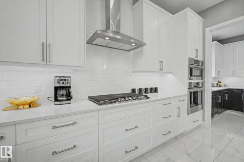 Gourmet kitchen featuring white shaker cabinetry, stainless steel appliances, a built-in oven and microwave, a gas cooktop with a range hood, and white subway tile backsplash - 3036 59 Avenue, Rural Leduc County, AB 