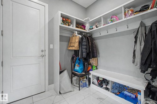 Entryway featuring white paneled door, marble-look tile flooring, built-in shelving, wall-mounted coat hooks, and a built-in bench with storage cubbies - 3036 59 Avenue, Rural Leduc County, AB 
